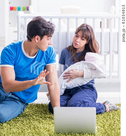 Young parents with their newborn baby sitting on the carpet 61034913