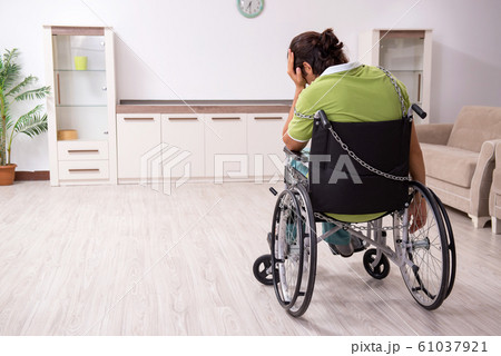 Young male invalid in wheel-chair suffering at home Young male invalid in wheel-chair suffering at home 61037921