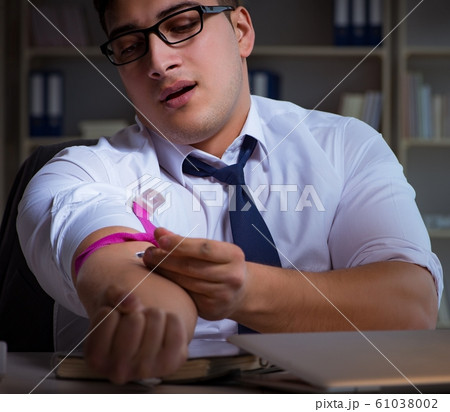 Businessman staying late in office for drugs 61038002