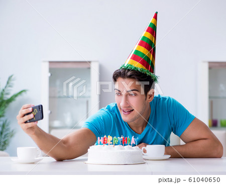 Young man celebrating birthday alone at home Young man celebrating birthday alone at home 61040650