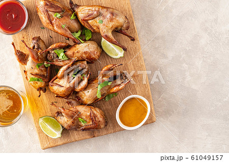 Baked quail with sauces, lime and beer on a wooden board. Baked quail with sauces, lime and beer on a wooden board. 61049157