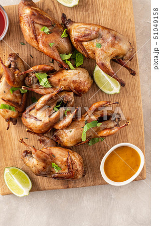Baked quail with sauces, lime and beer on a wooden board. Baked quail with sauces, lime and beer on a wooden board. 61049158