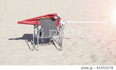 red sun umbrella on a chair on the beach 61050278