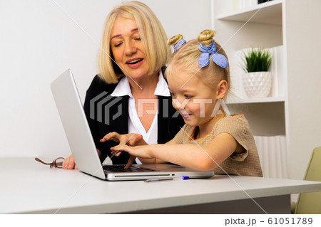 Teacher with little girl typing on the laptop in the classroom. 61051789