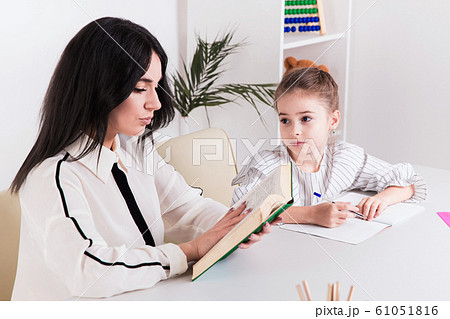 Pretty family concept. Mom and daughter sitting together and studying at home. Pretty family concept. Mom and daughter sitting together and studying at home. 61051816
