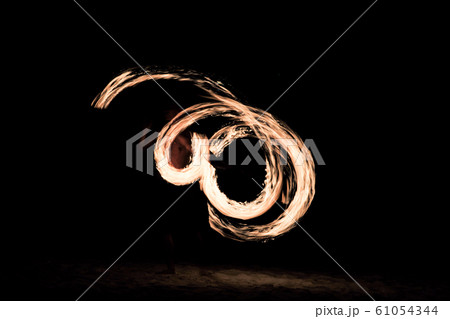 Motion blurred portrait of man dances with fire on the beach with dark night background Motion blurred portrait of man dances with fire on the beach with dark night background 61054344