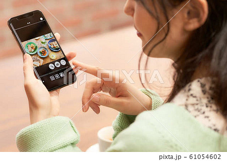ランチの写真を見る女性の手元 61054602