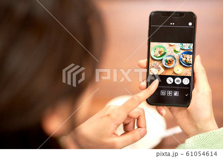 ランチの写真を見る女性の手元 61054614