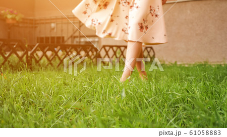 slim lady in dress bare feet walk along fresh green grass slim lady in dress bare feet walk along fresh green grass 61058883