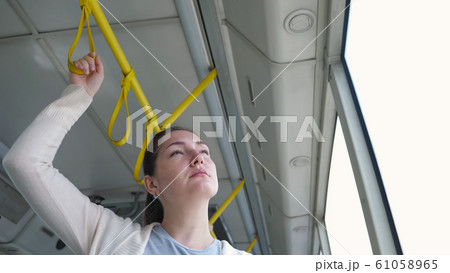 pretty woman stands in tram holding handrail travelling to city 61058965
