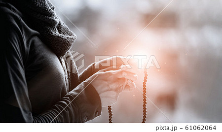 Woman hands praying and holding a beads rosary with Jesus Christ on lighting background, black&white, religious faith concept . 61062064