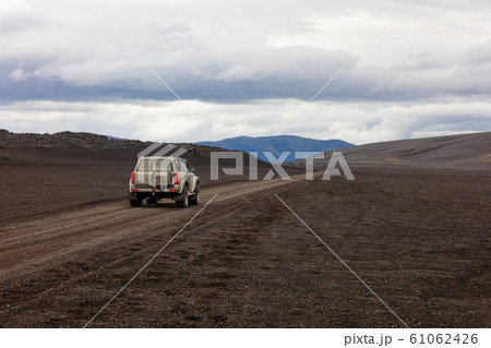 SUV on dirt road against cloudy sky SUV on dirt road against cloudy sky 61062426