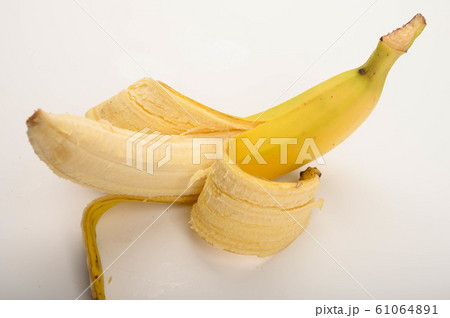 One ripe yellow partially peeled banana on a white 61064891