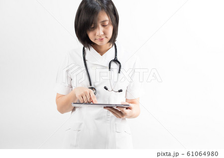 Young asian nurse with a stethoscope using a digital tablet, isolated over white background. Young asian nurse with a stethoscope using a digital tablet, isolated over white background. 61064980