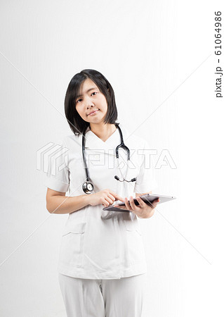 Young asian nurse with a stethoscope using a digital tablet, isolated over white background. 61064986