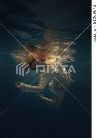 Girl in a beautiful dress swims underwater 61068643