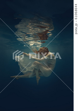 Girl in a beautiful dress swims underwater 61068644