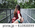Close up of hand rear traveler couple love hold hand while walking on forest, travel concept	 61068899