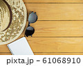 Eyeglasses and notepad with woven hat on wooden table of brown, travel and holiday concept 61068910