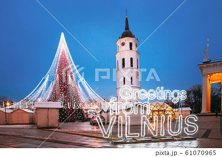 Vilnius, Lithuania. Christmas Tree, Sign Greetings From Vilnius Near Bell Tower Of Vilnius Cathedral At Cathedral Square In Evening New Year Christmas Xmas Illuminations. Unesco World Heritage Site 61070965