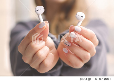 White wireless airpods in female hands. Modern mobile technology. 61073061