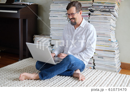 Male architect in a white shirt works at a laptop, smiling. 61073470