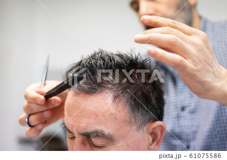 Barber trimming hair of old man at barber shop. 61075586