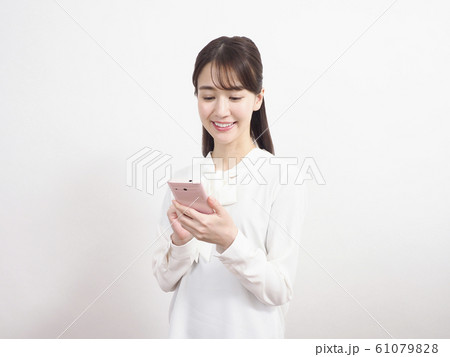 ピンクのスマホを見て微笑む女性 ピンクのスマホを見て微笑む女性 61079828