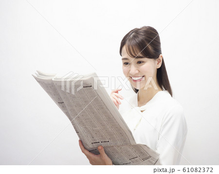新聞の株式欄を見て微笑むビジネスウーマン 61082372