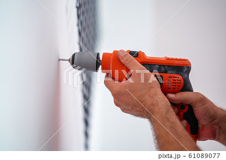 Drilling a hole on the wall for construction or renovation Drilling a hole on the wall for construction or renovation 61089077