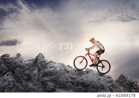 Riding mountain bike on the rocks against cloudy sky 61089178