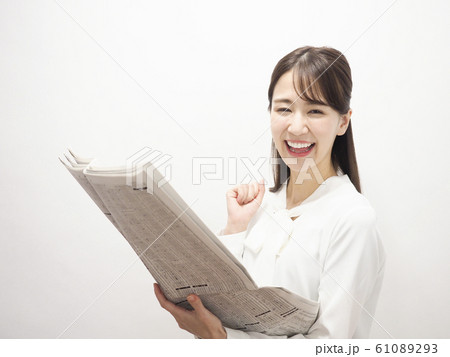 新聞の株式欄を見て微笑むビジネスウーマン 61089293