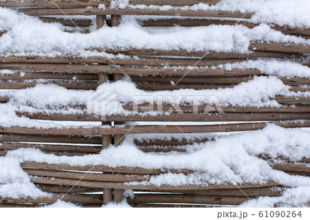 A fence of wicker branches covered in snow. A fence of wicker branches covered in snow. 61090264