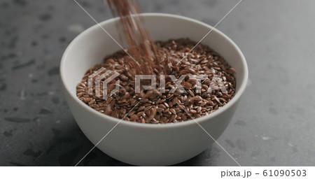 closeup flaxseed falling into white bowl on terrazzo countertop closeup flaxseed falling into white bowl on terrazzo countertop 61090503