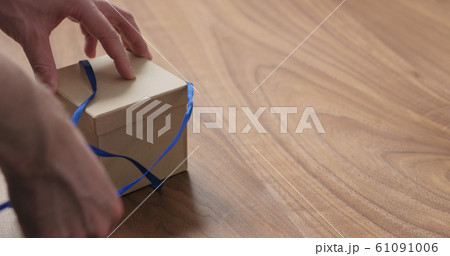 man hands opens eco friendly paper gift box with blue ribbon on walnut table with copy space man hands opens eco friendly paper gift box with blue ribbon on walnut table with copy space 61091006