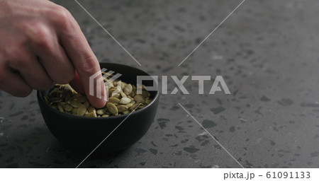 man hand takes pumpkin seeds from black bowl with copy space man hand takes pumpkin seeds from black bowl with copy space 61091133