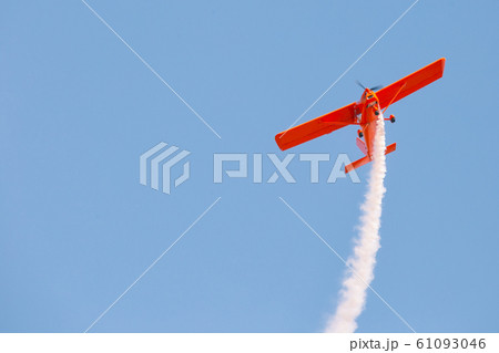 Red glider plane emits white smoke in blue sky Red glider plane emits white smoke in blue sky 61093046