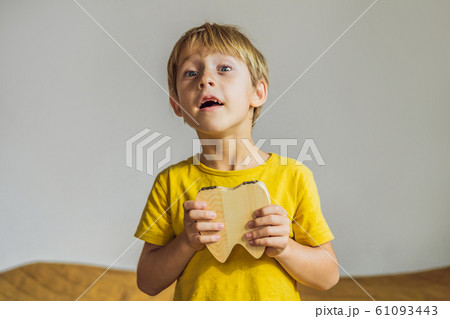 A boy, 6 years old, holds a box for milk teeth. Change of teeth 61093443
