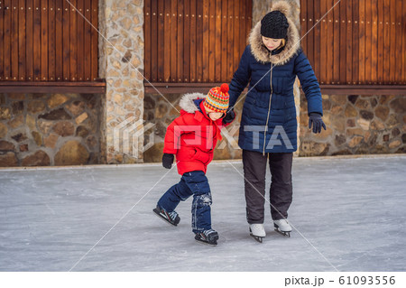 young mother teaching her little son ice skating at outdoor skating rink. Family enjoy winter on ice young mother teaching her little son ice skating at outdoor skating rink. Family enjoy winter on ice 61093556