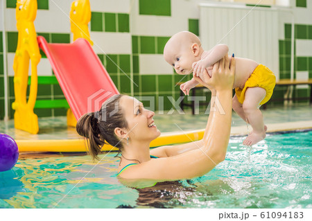 Beautiful mother teaching cute baby girl how to swim in a swimming pool. Child having fun in water Beautiful mother teaching cute baby girl how to swim in a swimming pool. Child having fun in water 61094183