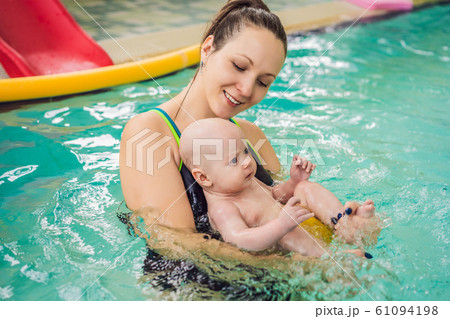 Beautiful mother teaching cute baby girl how to swim in a swimming pool. Child having fun in water Beautiful mother teaching cute baby girl how to swim in a swimming pool. Child having fun in water 61094198