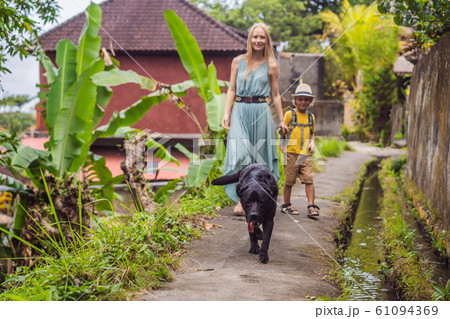 Mother and son tourists in Bali walks along the narrow cozy streets of Ubud. Bali is a popular 61094369