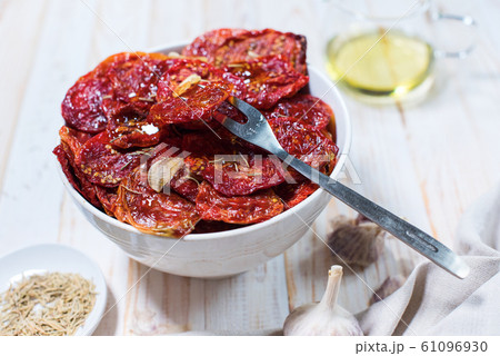 Dried tomatoes with garlic in bowl on white 61096930