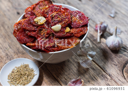 Dried tomatoes with garlic in bowl dark wooden 61096931