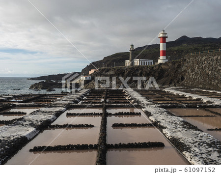 View of Fuencaliente salinas or saltworks and two lighthouse, old stone and white-red striped with volcanic rock field.La Palma, Canary Islands. Ocean, blue sky white clouds. View of Fuencaliente salinas or saltworks and two lighthouse, old stone and white-red striped with volcanic rock field.La Palma, Canary Islands. Ocean, blue sky white clouds. 61097152