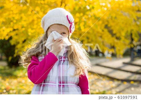 Girl child with cold rhinitis on autumn background, flu season, allergy runny nose 61097591