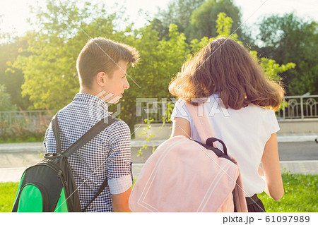 Children teenagers go to school, back view. Outdoors, teens with backpacks 61097989