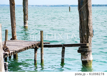 Old bridge with bars with seagulls on landscape of Lake Garda with town Limone sul Garda 61098278