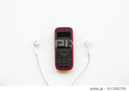 older mobile phone press the button old generation with earphone arrangement flat lay style  61106256