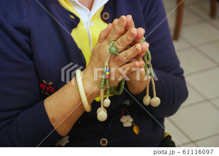 Woman press the hands together at the chest in sign of respect and hold prayer beads on hands for praying Woman press the hands together at the chest in sign of respect and hold prayer beads on hands for praying 61116097